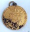 Gold coin has inscriptions and image of a coin above a shield
