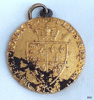 Gold coin has inscriptions and image of a coin above a shield