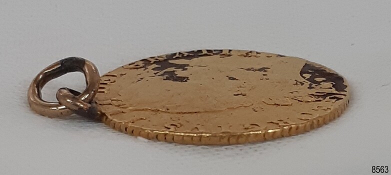 Gold ring is buckled, coin edge is worn in  places, Recessed areas of the front surface are a dark colour 