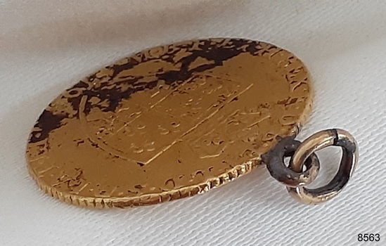 Coin has a reed edge. Loop is fitted into the edge and has a ring in it