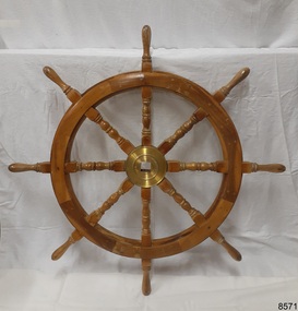 Front of eight spoked wooden ship's wheel with brass hub 