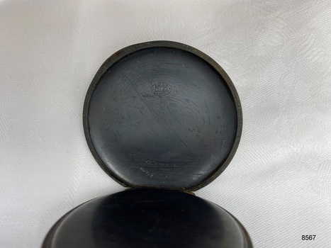 View inside the back cover of the fob watch showing stamped inscription and number.