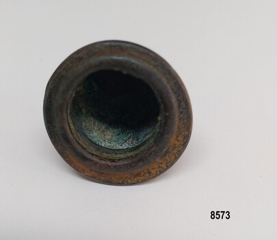 The base is round with a defined edge. The internal space is bell shaped with some evidence of verdigris on the surface.