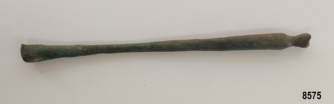 Slender brass rod tapering into the center and widening at each end