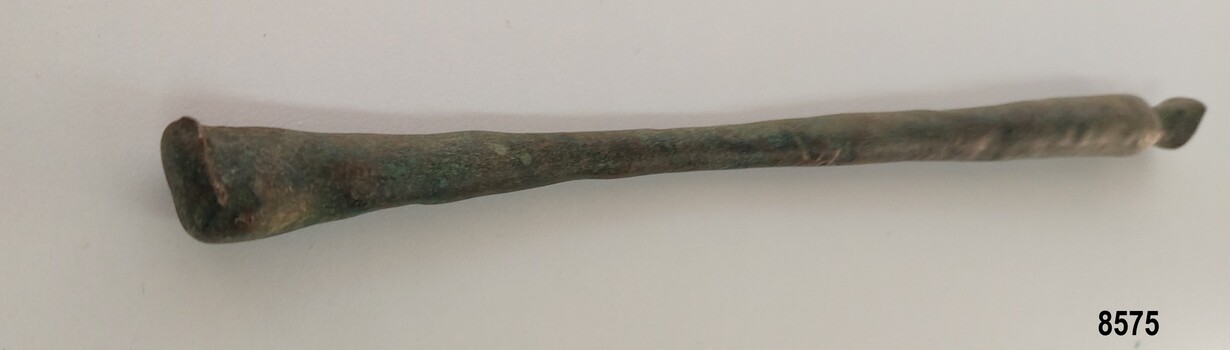 Slender brass rod tapering in the center and widening at each end