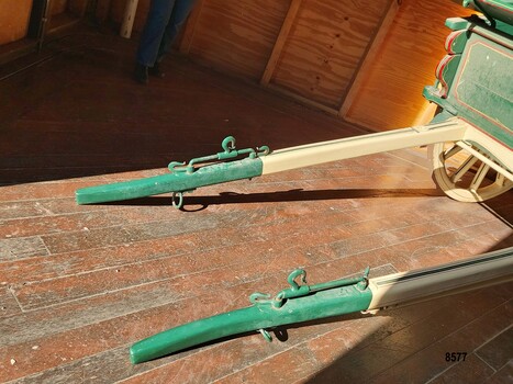 Cream and green wooden shafts with metal hooks and fixtures for attaching the harness 