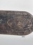Close up view of an indistinctive maker's stamp on the end of the leather strap