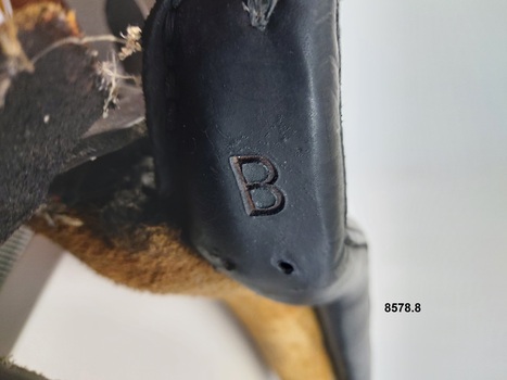 Close up of a letter B stamped onto leather near the top opening of the collar