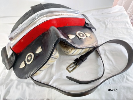 Leather saddle used as part of a Clydesdale's show harness. It is padded and has red and silver ornamentation.