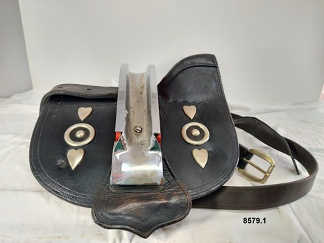 Side view of leather saddle used as part of a Clydesdale's show harness showing metal ornamentation and metal back strap holder