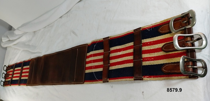 Leather and canvas belly band featuring red, white and blue stripes and three buckles at each end