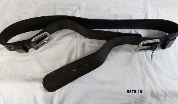 Wide leather strap belonging to a horse harness with a buckle and notches at each end