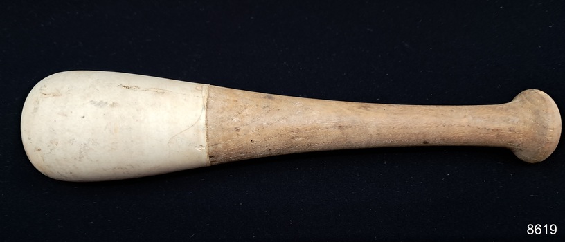 Wooden handle with a knob on top, flaring out to a white ceramic end with a rounded base