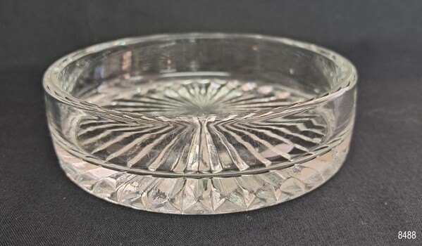 Bowl has thick base and rounded sides. It has a cut glass pattern on the base