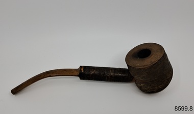 A collection of six pipes. Two of the pipes are resting in their protective cases. One of the pipes is the old fashioned clay type.
