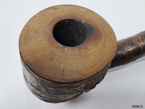 A collection of six pipes. Two of the pipes are resting in their protective cases. One of the pipes is the old fashioned clay type.