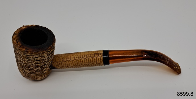 A collection of six pipes. Two of the pipes are resting in their protective cases. One of the pipes is the old fashioned clay type.