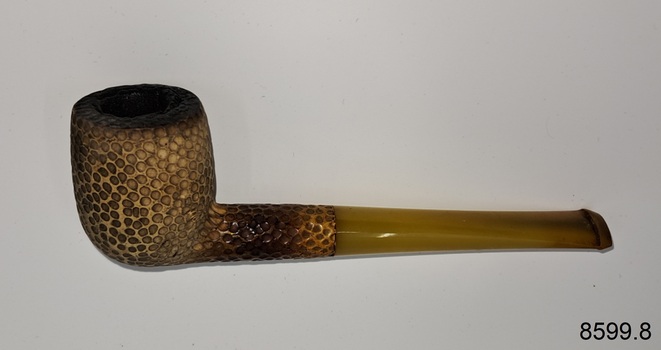 A collection of six pipes. Two of the pipes are resting in their protective cases. One of the pipes is the old fashioned clay type.