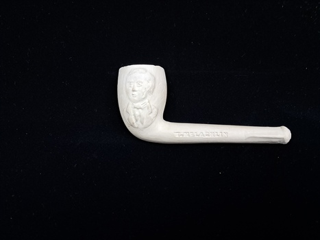 A collection of six pipes. Two of the pipes are resting in their protective cases. One of the pipes is the old fashioned clay type.
