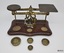 Set of metal scales on wooden base together with four different weights.