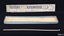 Unused white tapers in a blue cardboard box with printed label on lid