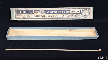 Unused white tapers in a blue cardboard box with printed label on lid