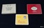 Three metal boxes, once containing cigarettes or cigars branded 'Ritmeester', 'Craven A' and 'De Reszke'.