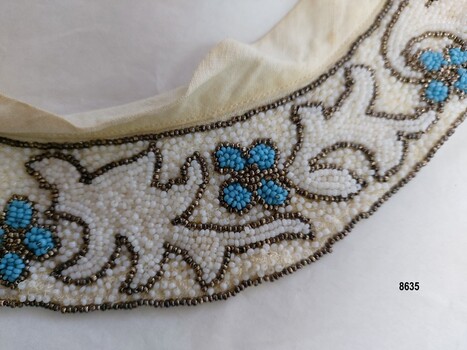 Detail on collar showing flower and leaf design with bronze bead borders and cotton bias lining at top