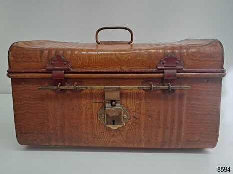 Brown woodgrain patterned camelback trunk with three latches and brass lock