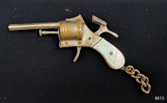 A cigarette lighter is shaped like a small pistol with a plastic handle and a short chain attached.