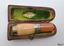Case has green lining with an inscription. It coutains a two-toned mouthpiece 
