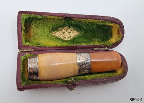 Case has green lining with an inscription. It coutains a two-toned mouthpiece 