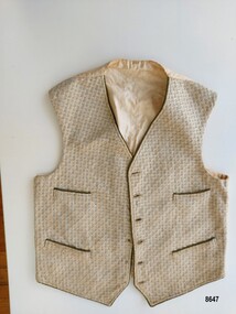 Front view of vest showing patterned fabric, four pockets and buttonholes