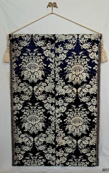 Dar blue and cream richly patterned brocade fumaric hanging from a rod with tastels.