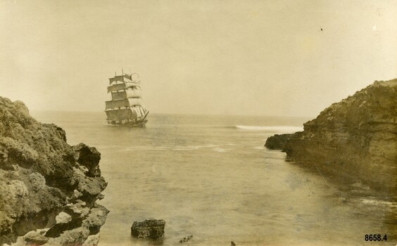 Postcard with sepia photo of a sailing ship approaching two rocky headlands