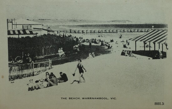 Figures sitting or standing in the foreground with a jetty and Breakwater behind