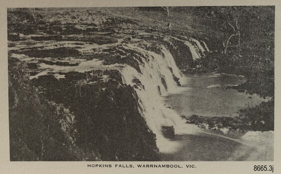 Wide and sort waterfall with vegetation in the background