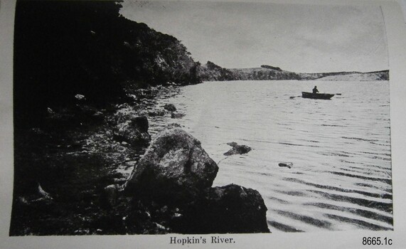 Black and white image showing a figure in a rowboat on a river
