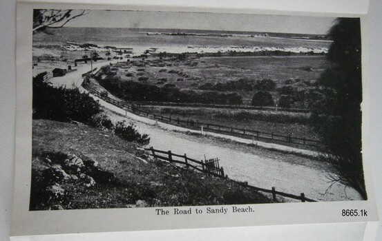 Curved road between land, sloping towards the sea