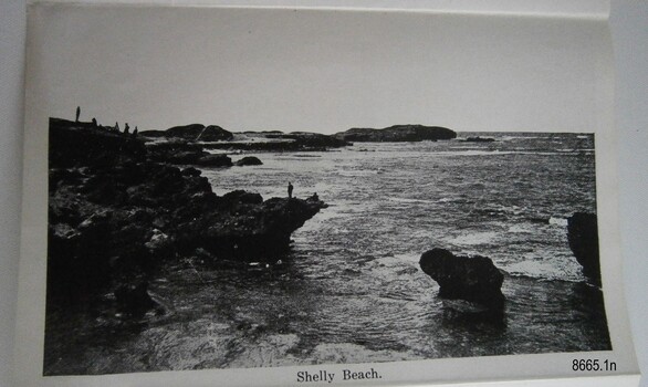 Figures on rocks beside a rocky ledge and the sea