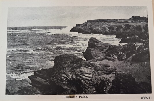 Black and white photograph of waves crashing against rocky cliffs on the shoreline