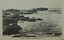 a rocky shelf beside a rocky shoreline. Waves are crashing against the cliffs.