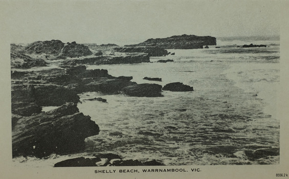 a rocky shelf beside a rocky shoreline. Waves are crashing against the cliffs.