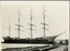 Black and white photograph of a four masted barque moored at a dock.