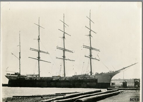 Black and white photograph of a four masted barque moored at a dock.