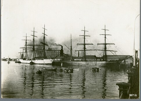 Black and white photograph showing two sailing ships moored at a dock