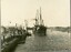 A steam ship with decorative flags is arriving at a pier