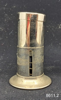 A two-piece round metal cigar piercer with a hollow spike in the middle of the base and a metal protective top.