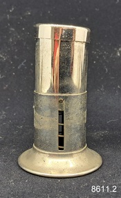 A two-piece round metal cigar piercer with a hollow spike in the middle of the base and a metal protective top.
