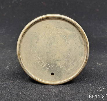 A two-piece round metal cigar piercer with a hollow spike in the middle of the base and a metal protective top.